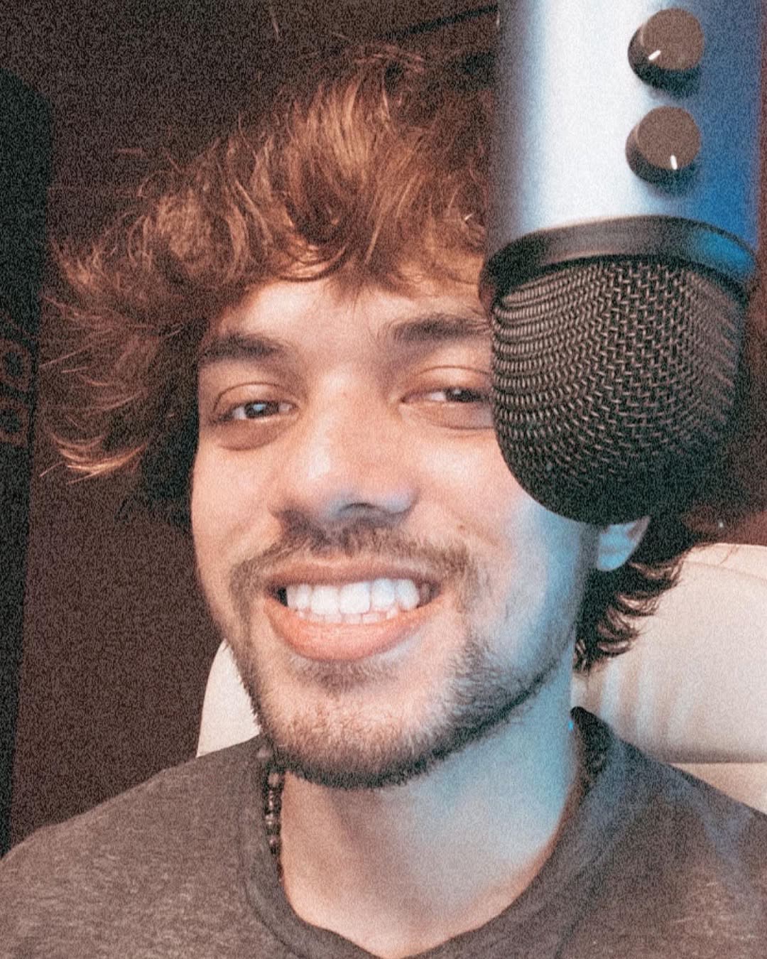Elio smiling beside a studio microphone.