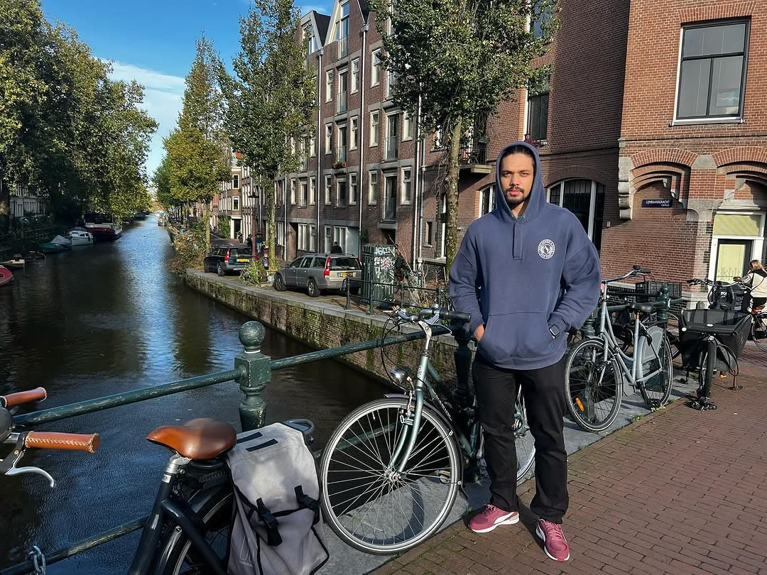 Elio standing by bikes on a canal bridge in Amsterdam.