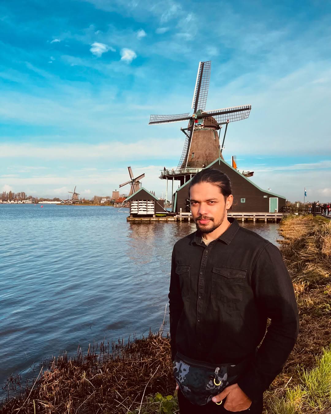 Elio by a lake in front of Dutch windmills.